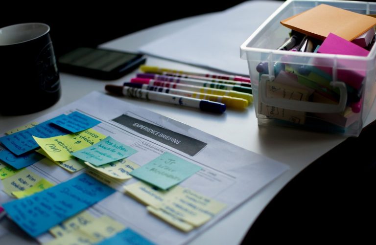 Workshop Ein Tisch mit Notizzetteln, Stiften, einem Kalender und einer Box voller Bürobedarf.